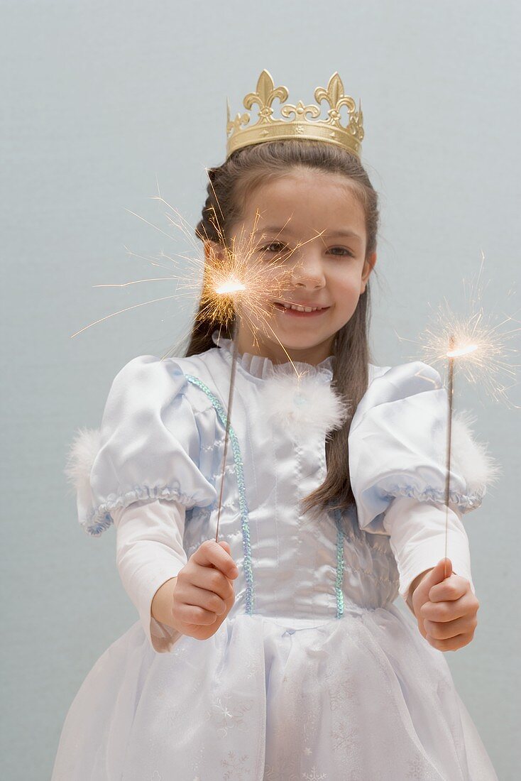 Little girl dressed as princess holding sparklers