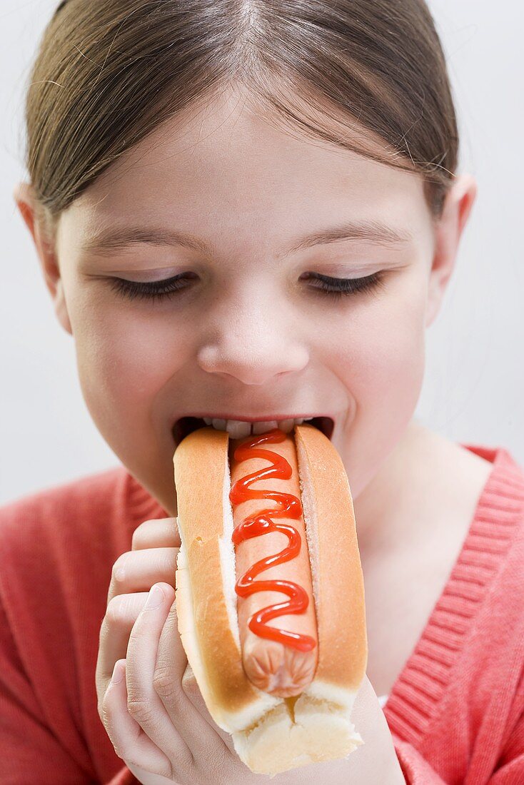 Girl biting into a hot dog