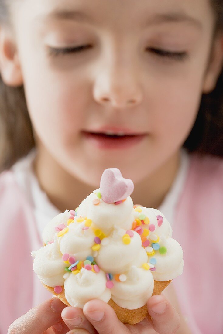 Little girl holding cupcake with cream and sugar confetti