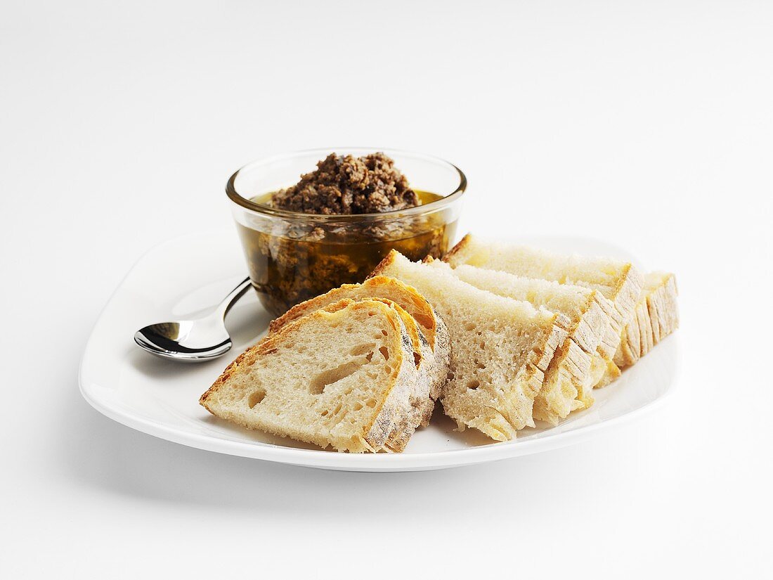 Tapenade und Brotscheiben auf Teller