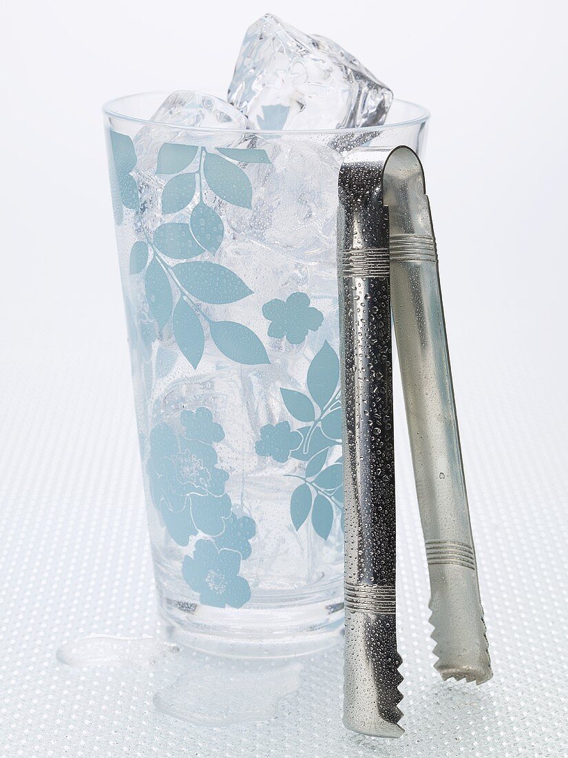 Ice cubes in a patterned glass and tongs