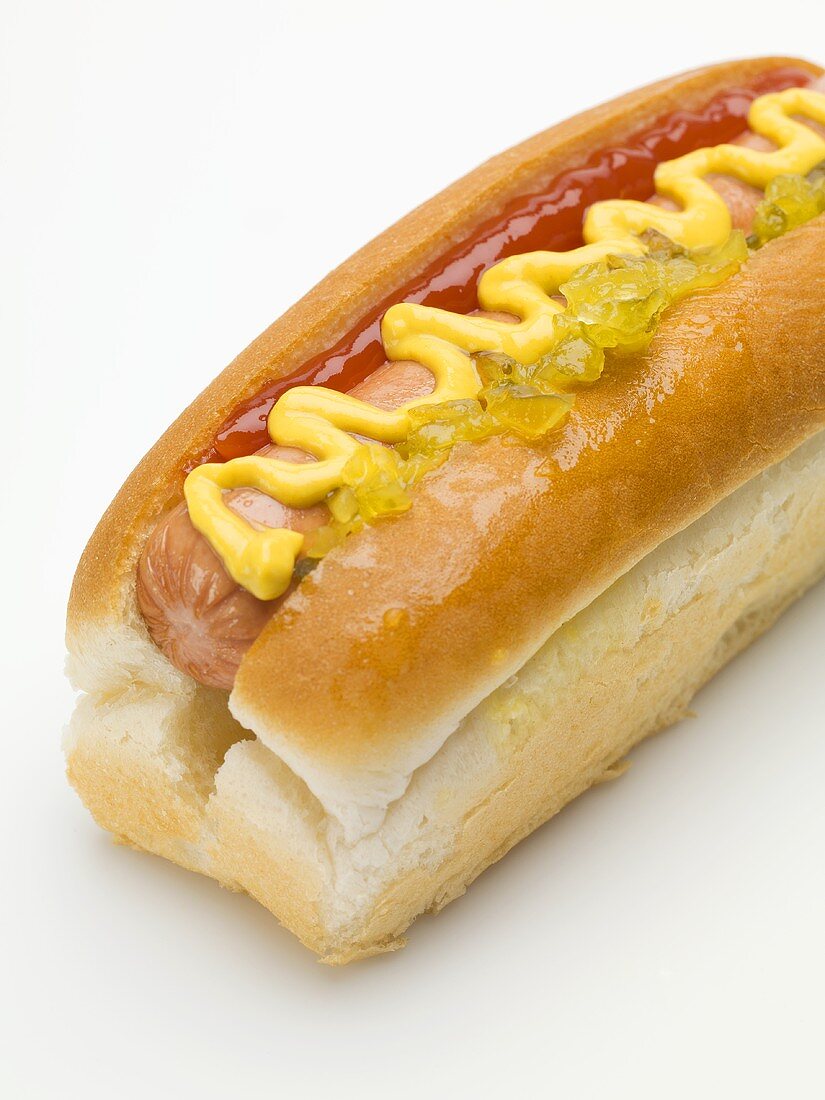 Ein Hot dog mit Senf, Ketchup und Gurken