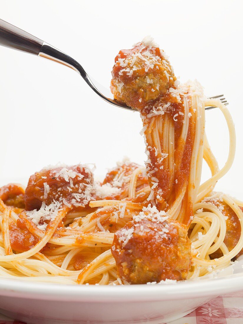 Spaghetti und ein Fleischbällchen in Tomatensauce auf einer Gabel