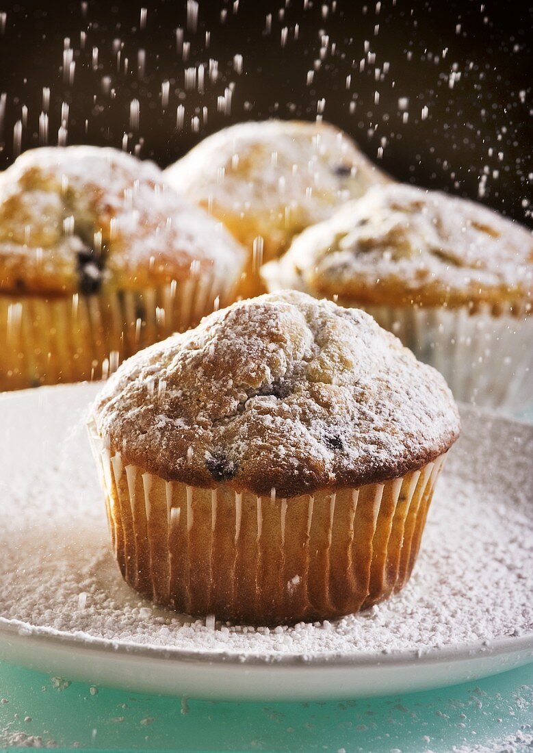Blueberry Muffins Being Dusted with Powdered Sugar