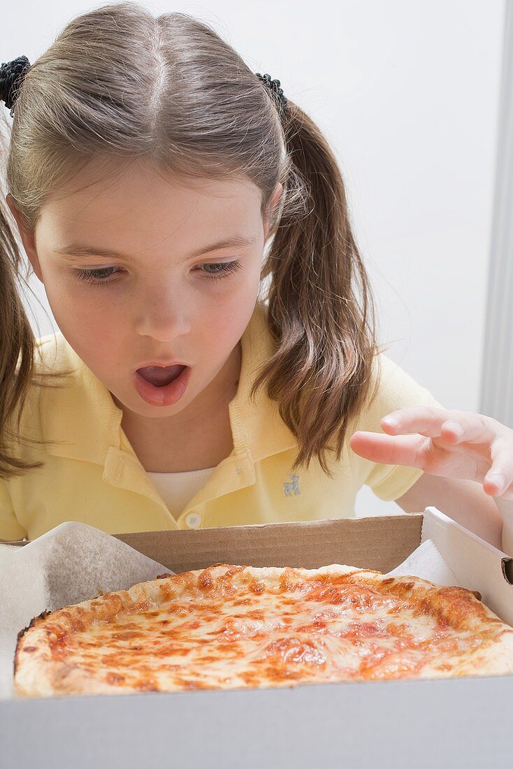 Girl looking in wonder at fresh pizza in box, 