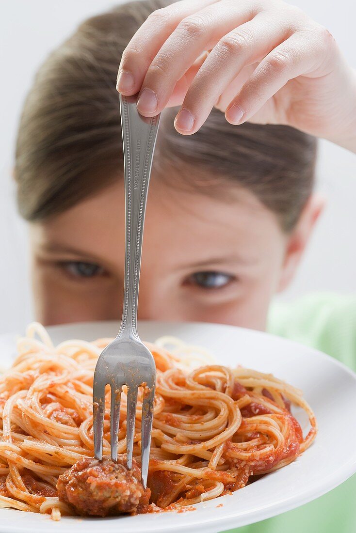 Girl spearing a meatball on a fork