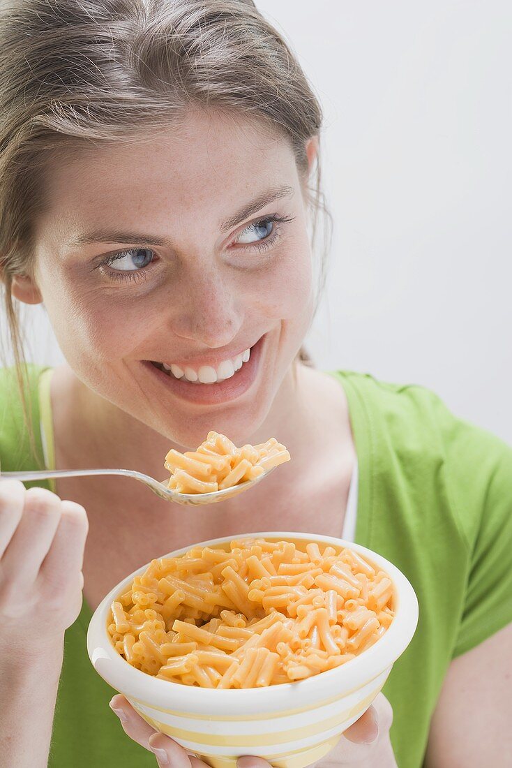 Smiling woman in green T-shirt eating pasta