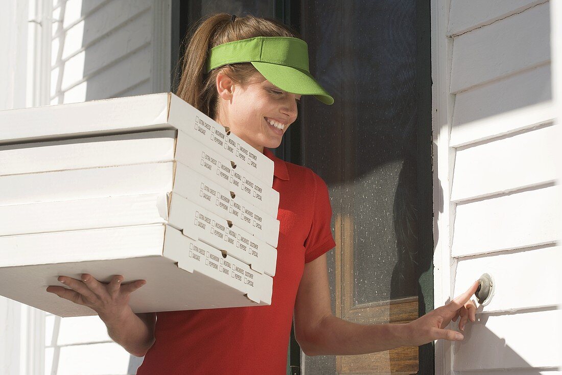 Junge Frau vom Pizzaservice klingelt an der Tür