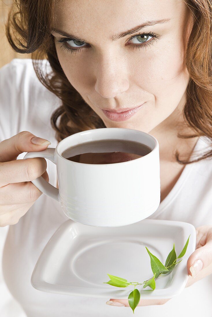 Junge Frau trinkt Kaffee im Bett