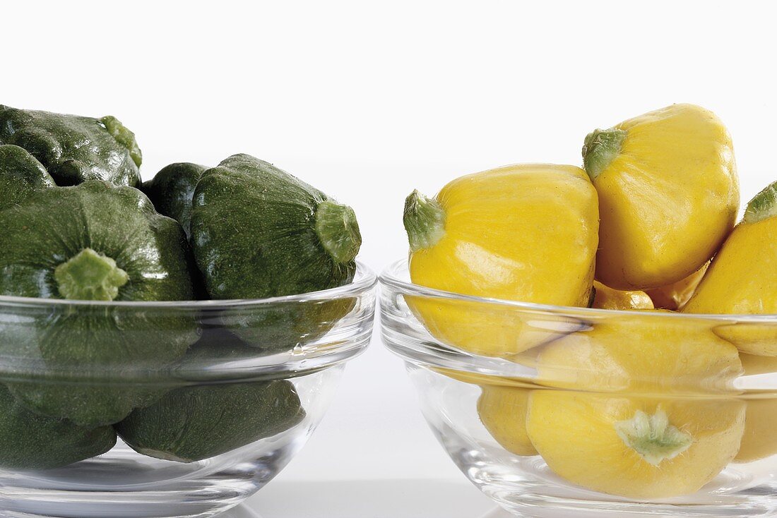 Green & yellow patty pan squashes in glass bowls (close-up)