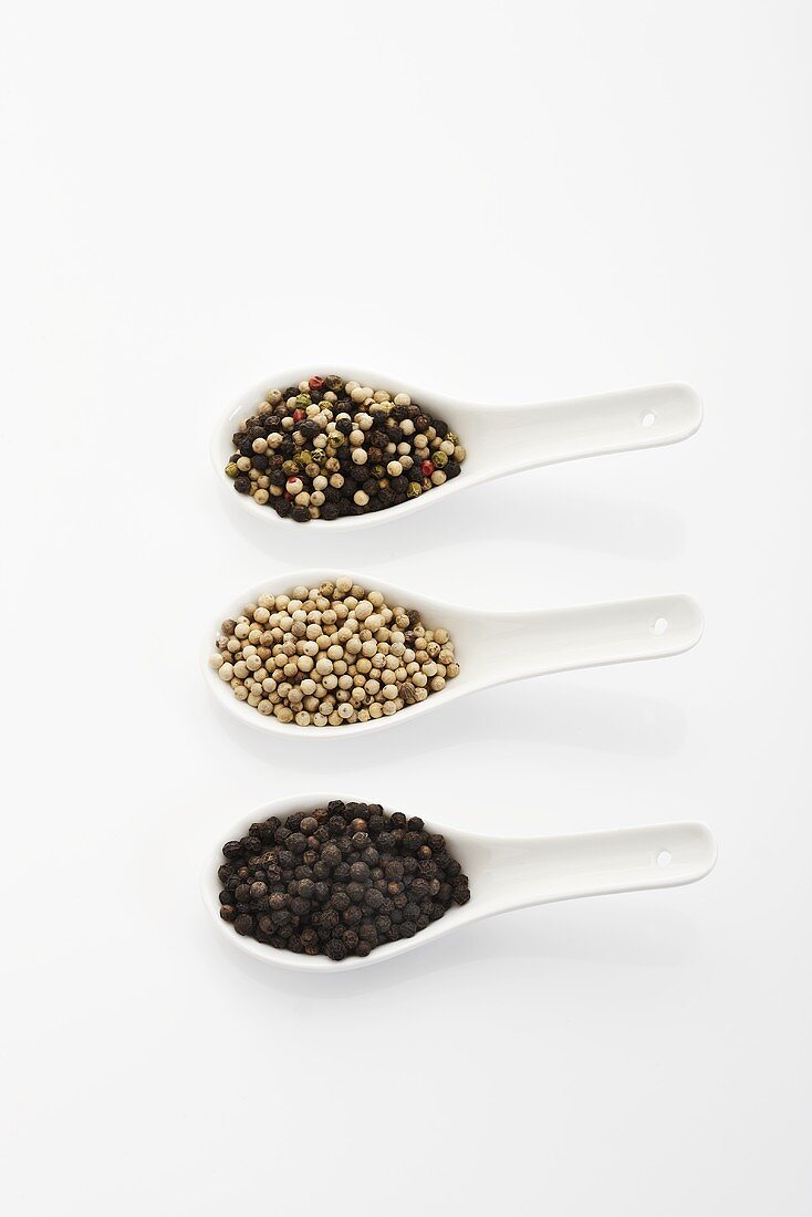 Different types of peppercorns in three spoons