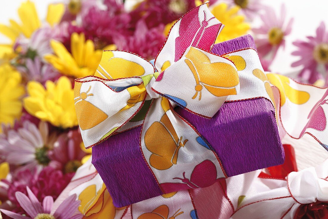 Wrapped gift with summery ribbon, chrysanthemums