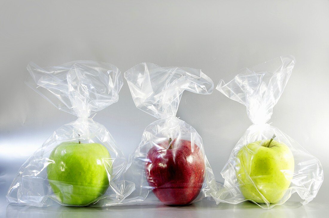 Three apples in plastic bags