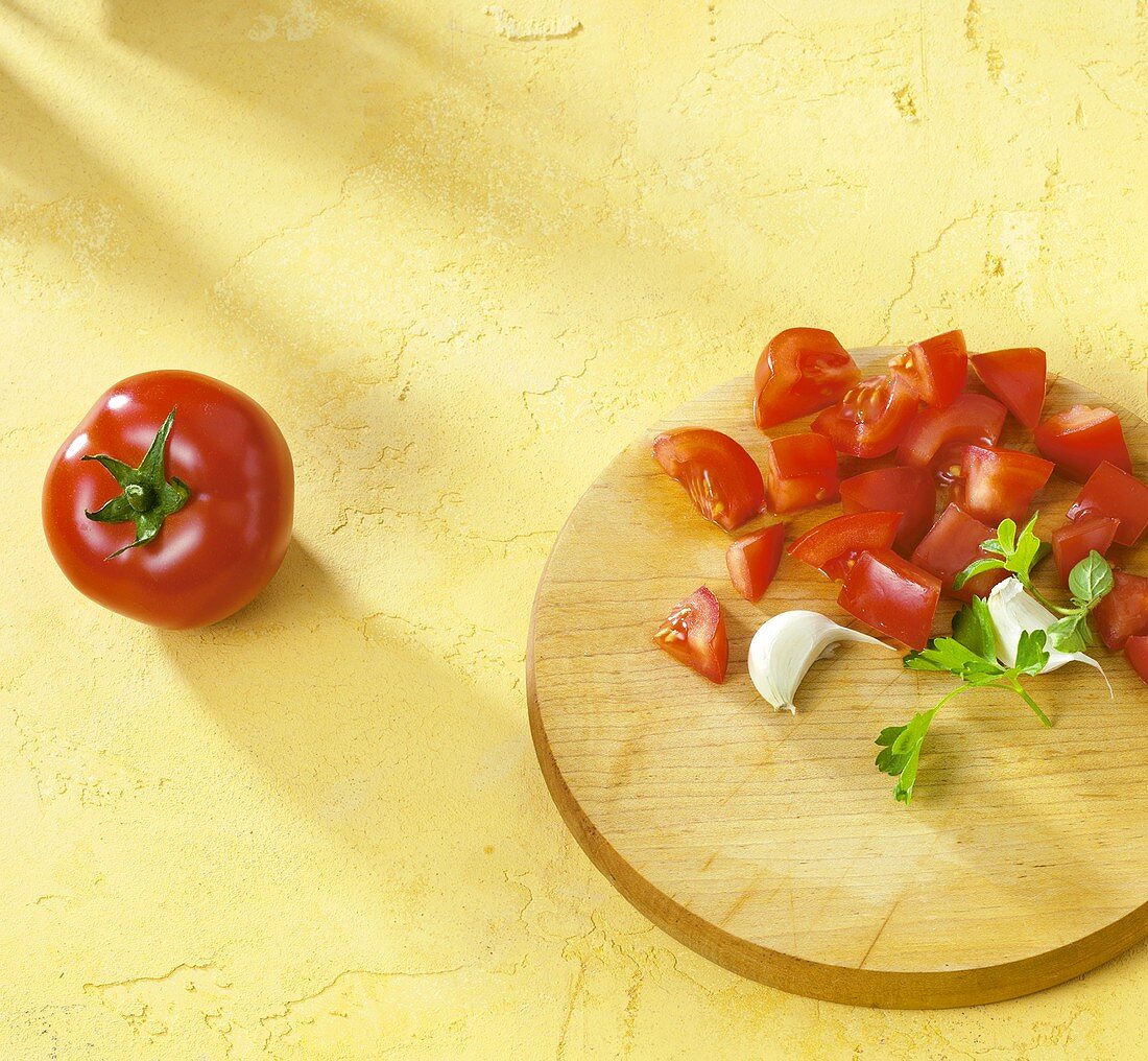 Tomatenwürfel, Knoblauch und Petersilie auf Schneidebrett