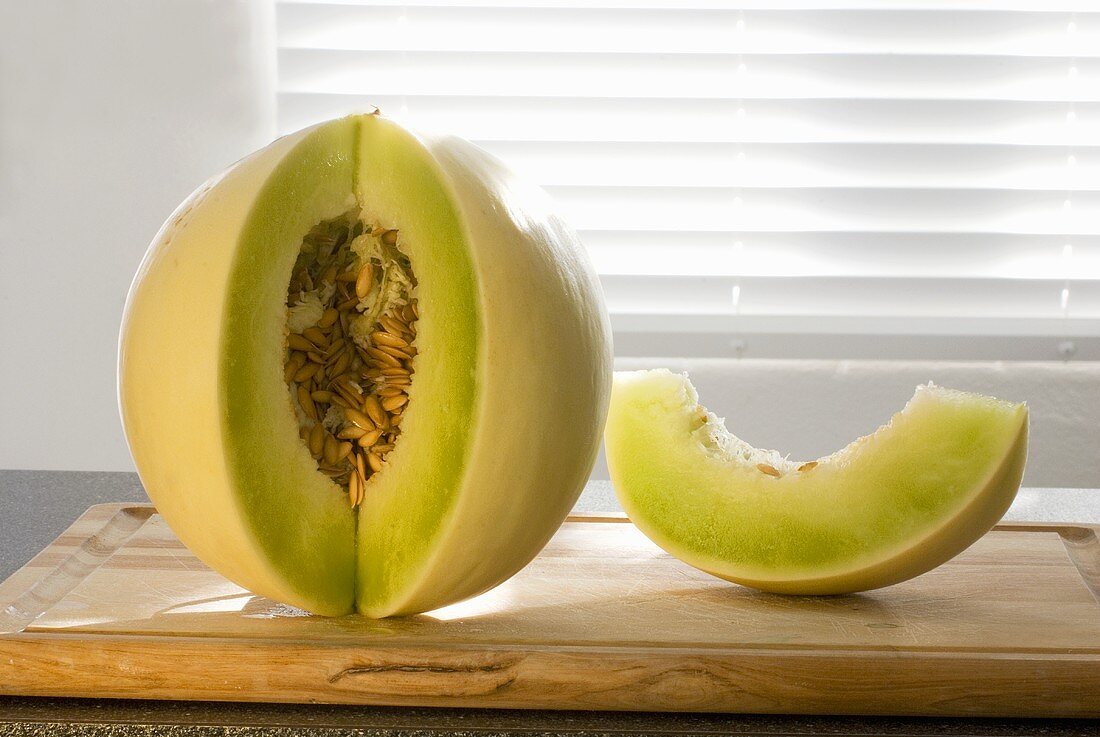 Honigmelone mit herausgeschnittener Spalte auf Schneidebrett