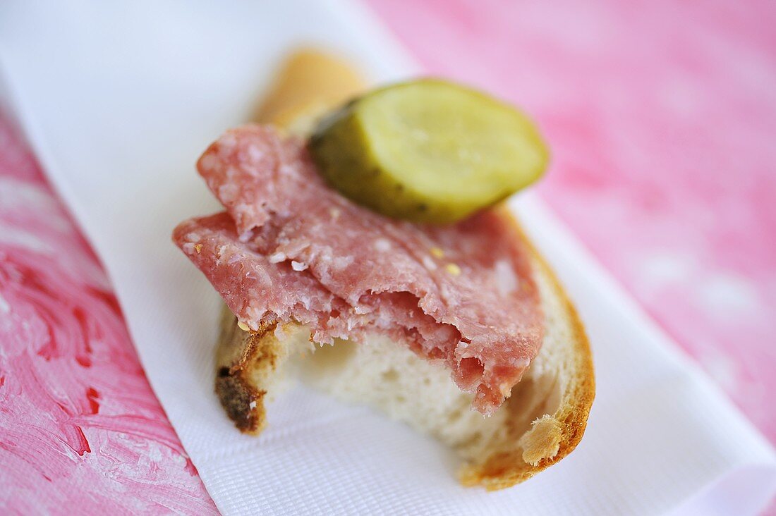 Salami and bread with gherkin, a bite taken