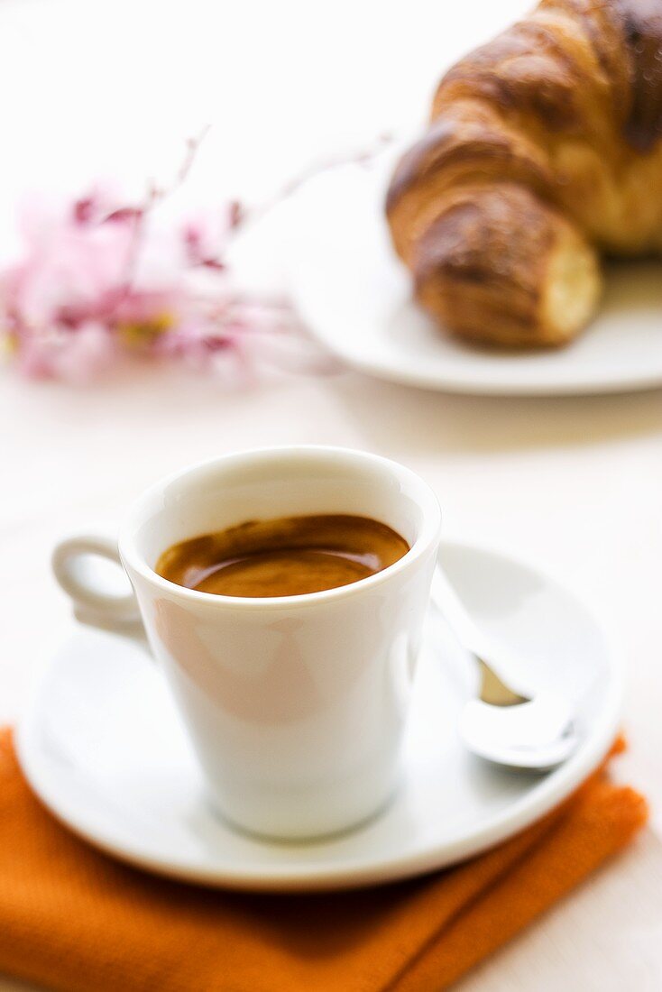A cup of espresso with croissant