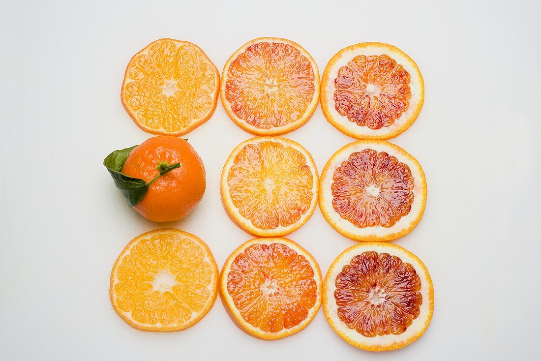 Ganze Clementine und verschiedene Orangenscheiben von oben