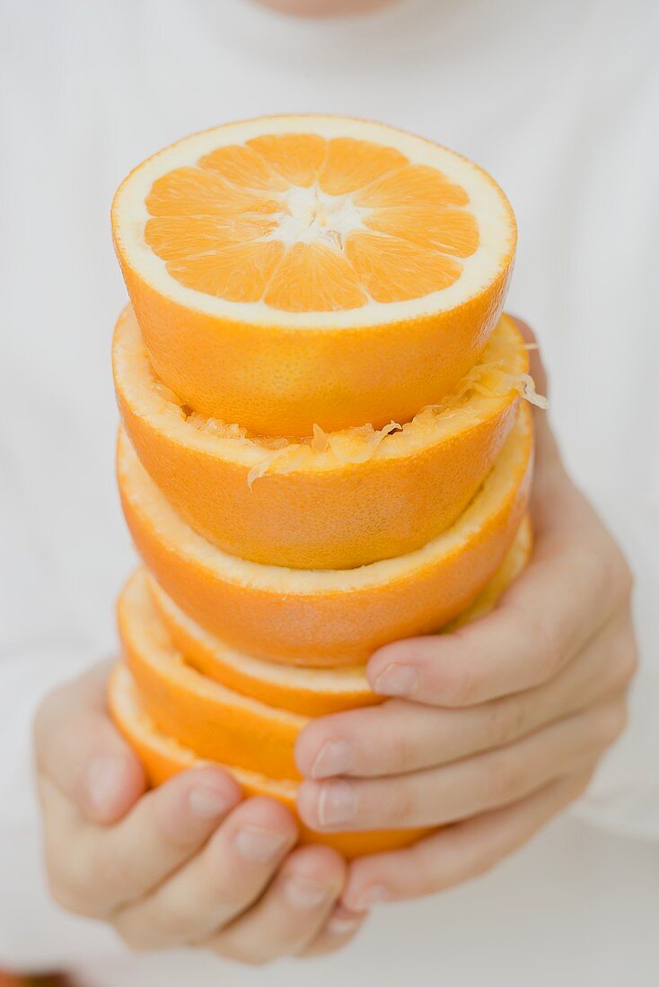 Child's hands holding stacked orange halves
