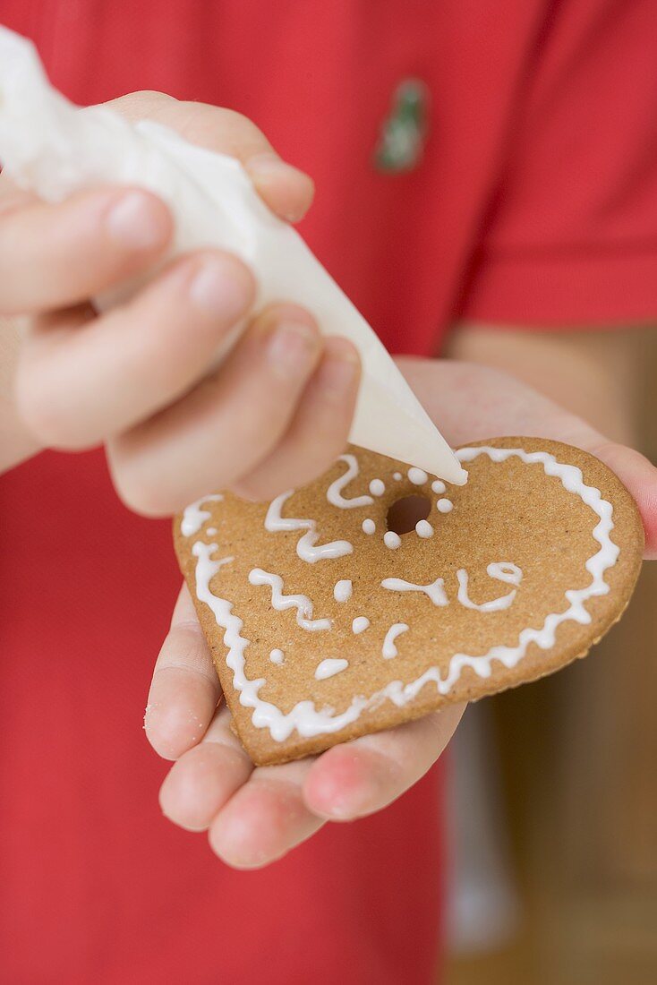 Child decorating biscuit with piping bag