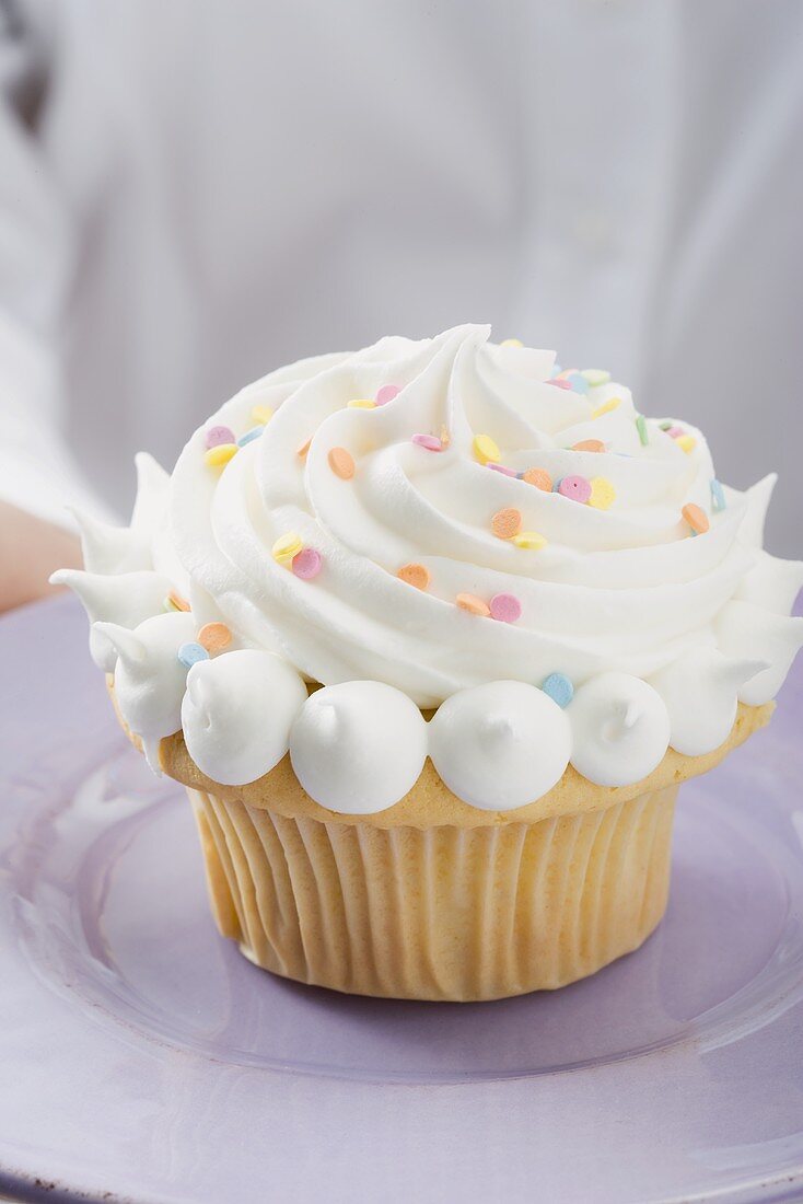 Hände halten Cupcake auf Teller