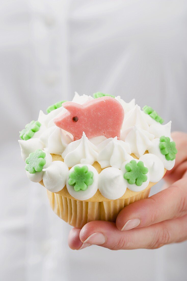 Hand hält Cupcake mit Marzipanschwein