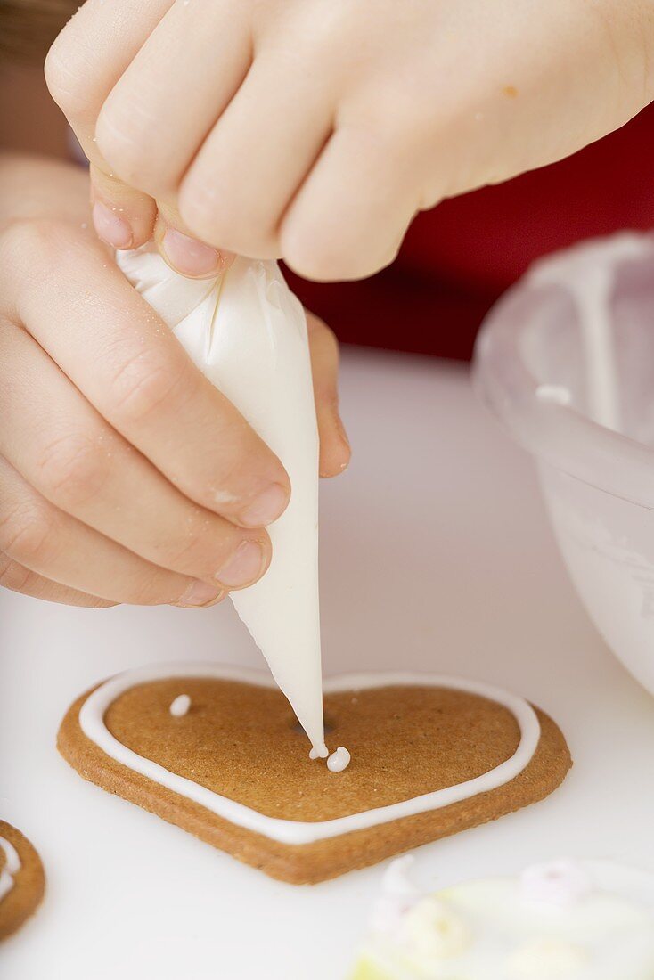 Child decorating biscuit with piping bag