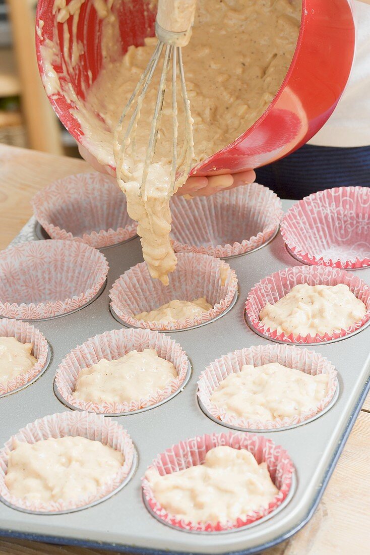 Putting muffin mixture into paper cases