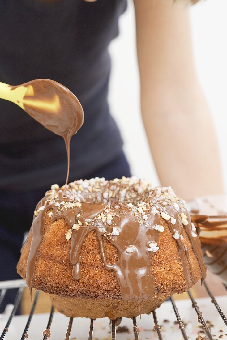 Kind verziert Napfkuchen mit Schokoguss