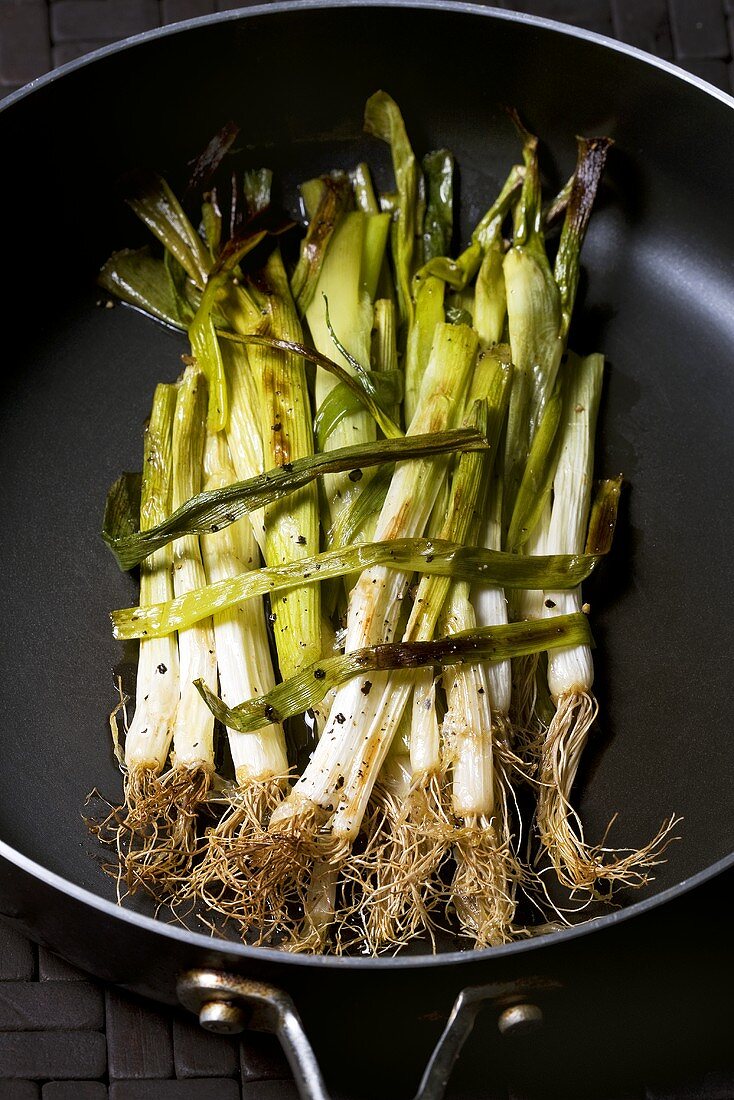 Oven-roasted spring onions in a frying pan
