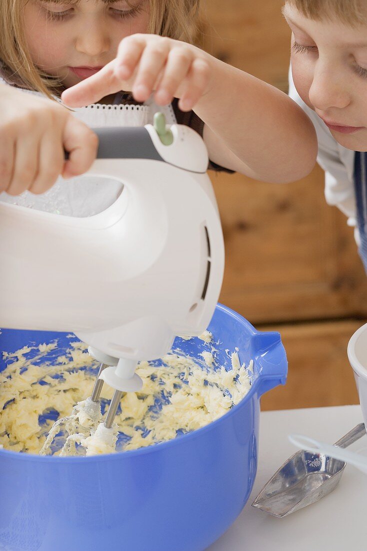 Kleines Mädchen rührt Butter mit Mixer