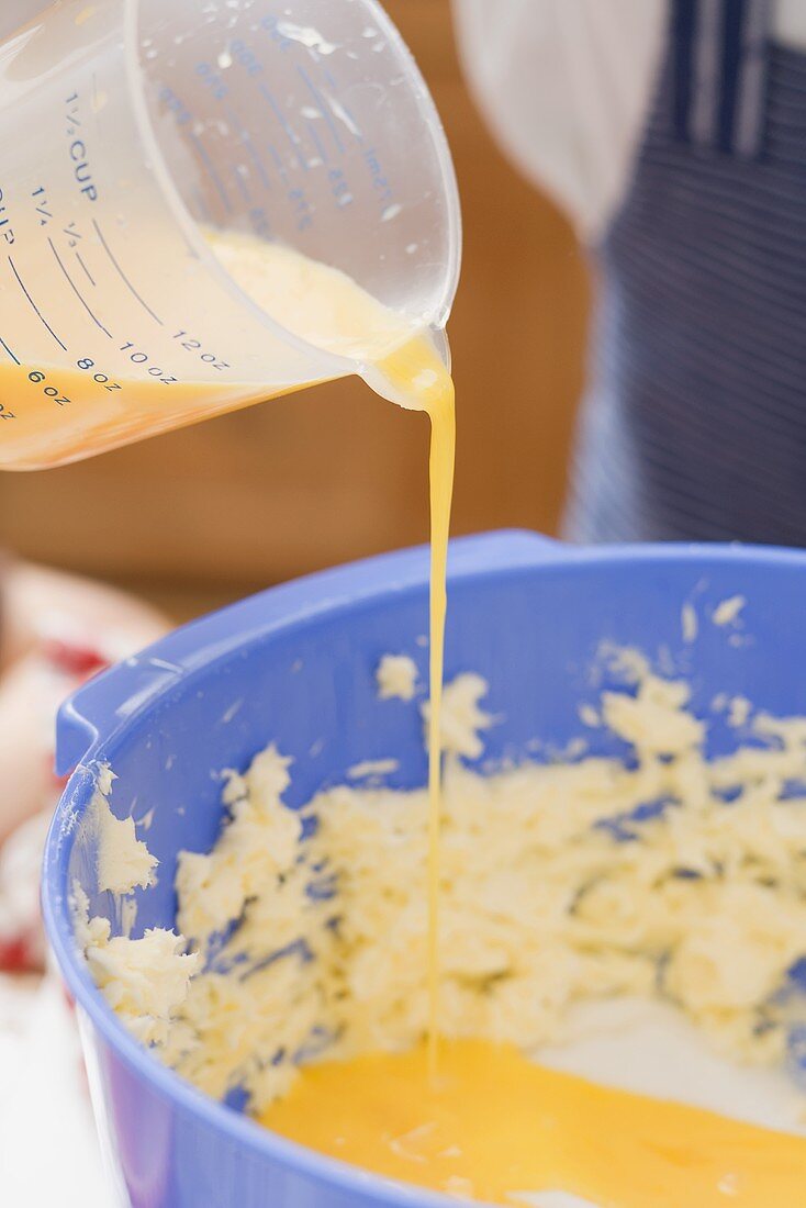 Child pouring egg yolk into butter mixture