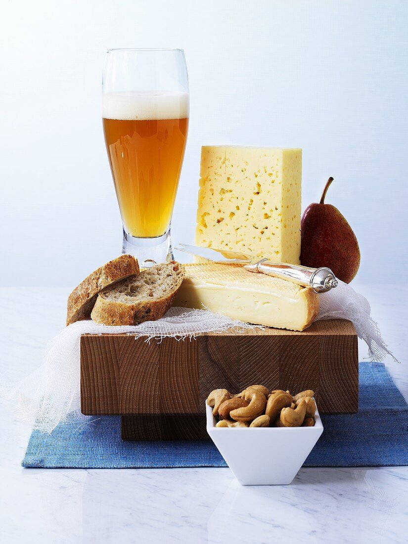 Käse mit Brot, Birne und Weissbier auf einem Brett