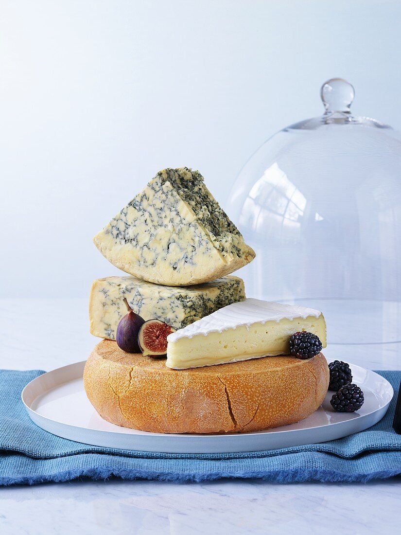 Various cheeses on cheese platter with figs, blackberries