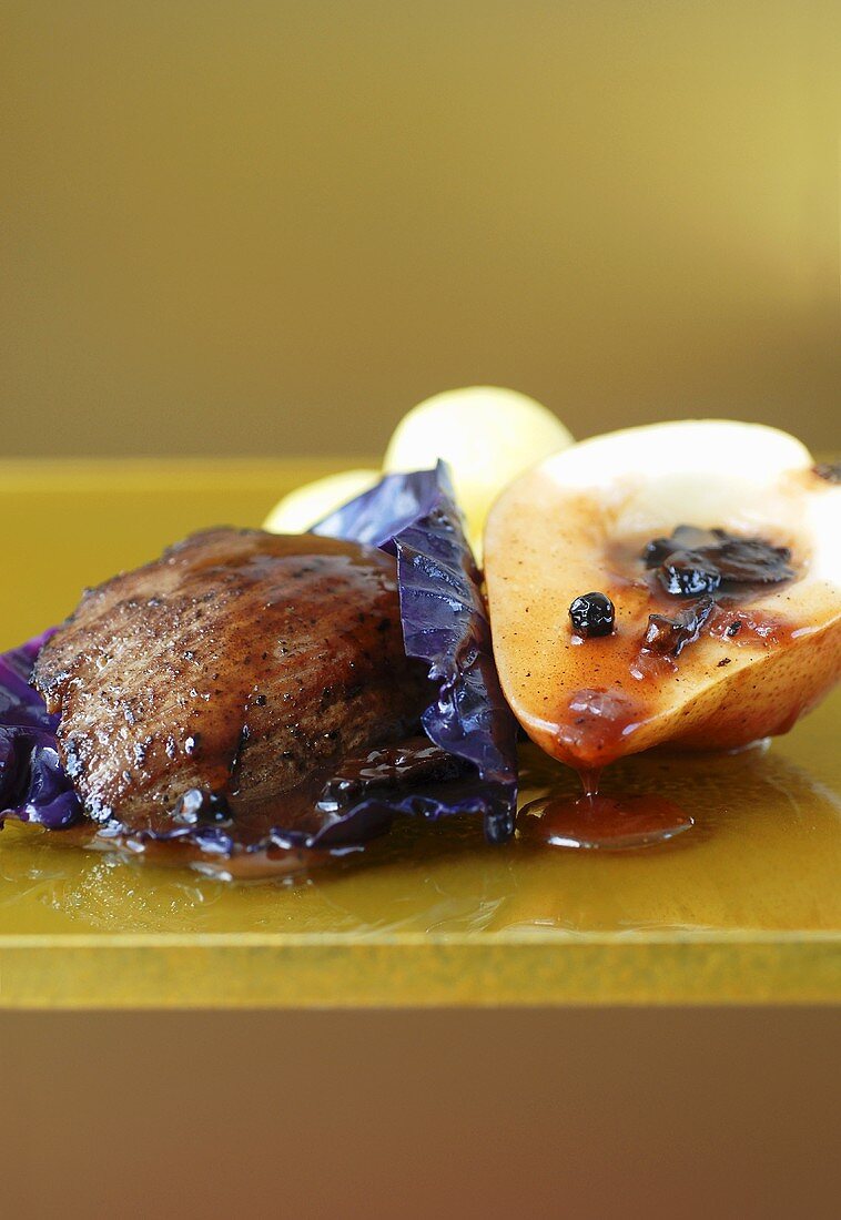 Venison fillet on red cabbage leaf with pear