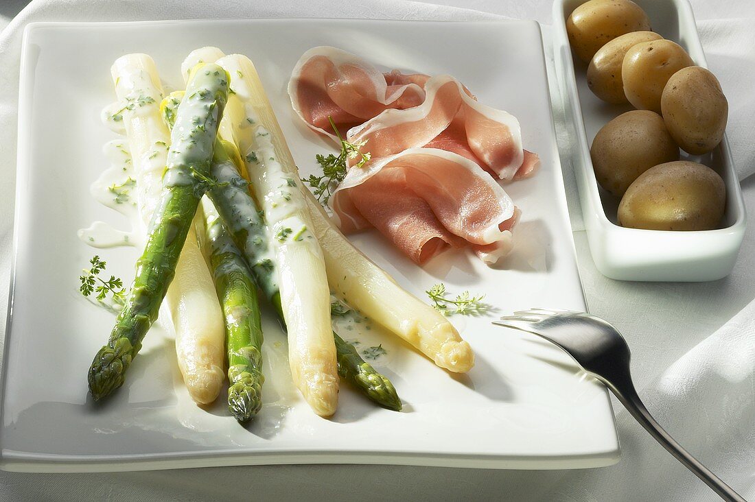 Asparagus with herb sauce, raw ham and potatoes
