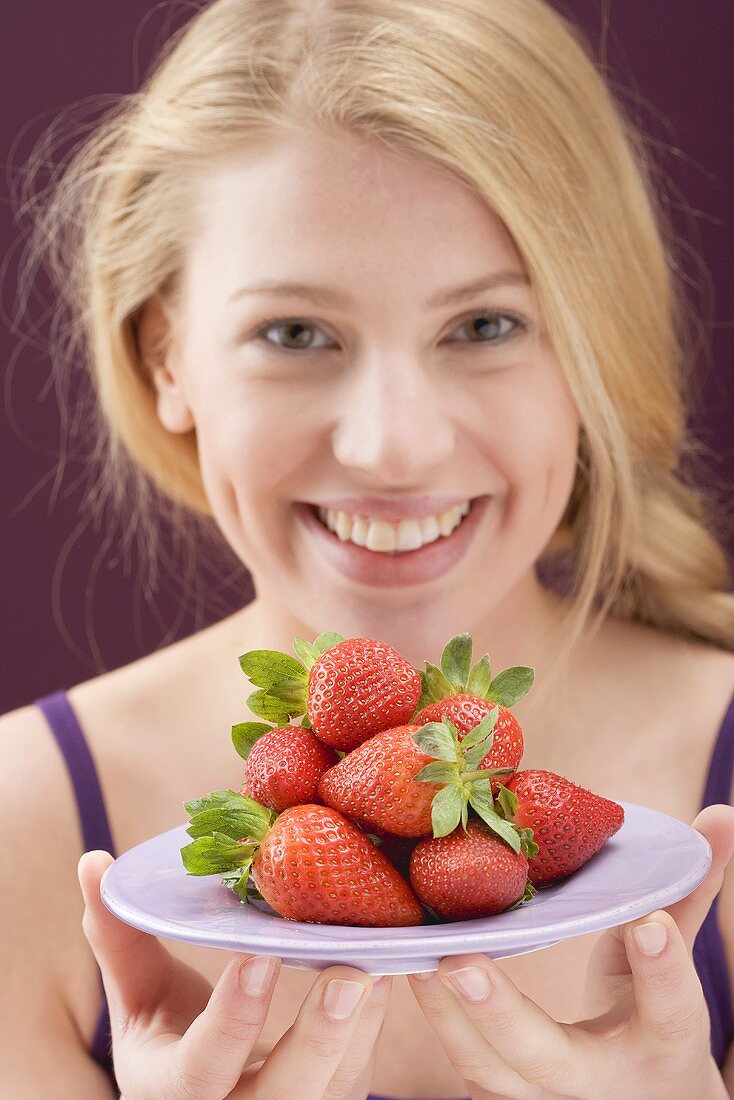 Frau hält Erdbeeren auf Teller