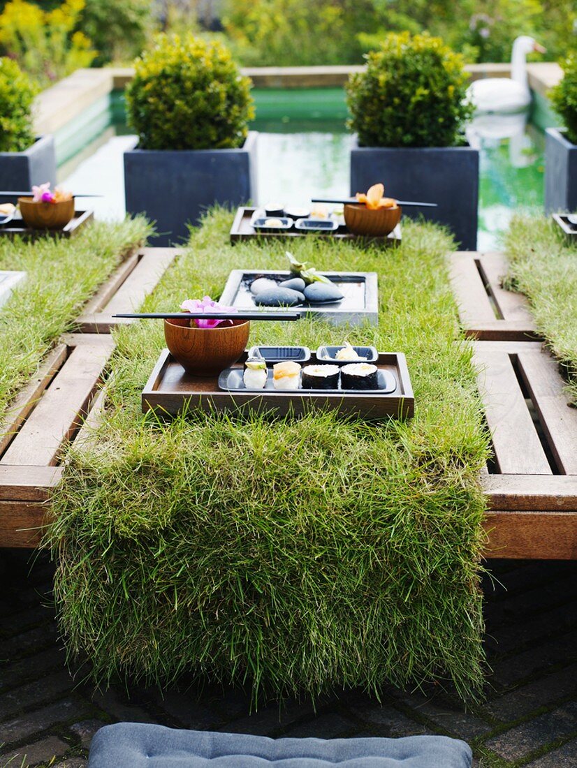 Laid table with turf and sushi tray out of doors