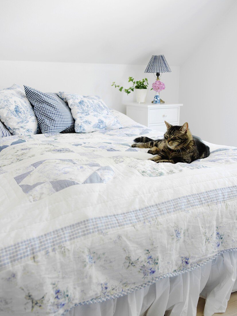 Schlafzimmer mit nostalgischem Doppelbett unter der Dachschräge und einer darauf ruhenden Katze