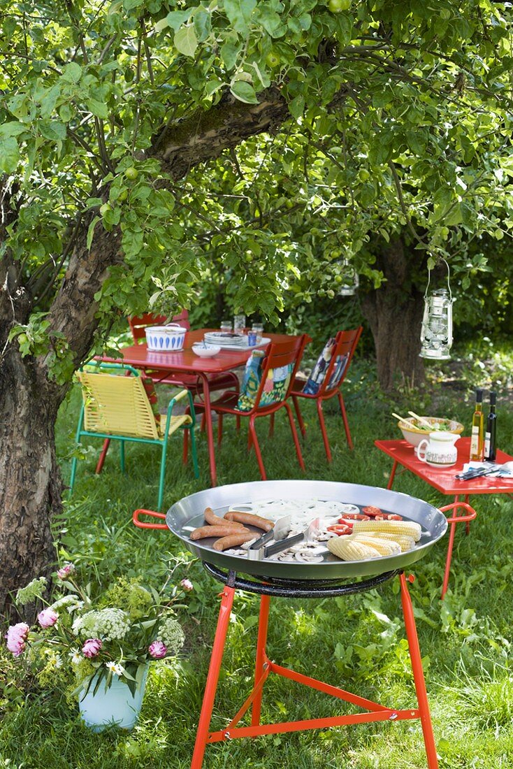 Gasgrill und Tisch mit Stühlen unter einem Baum