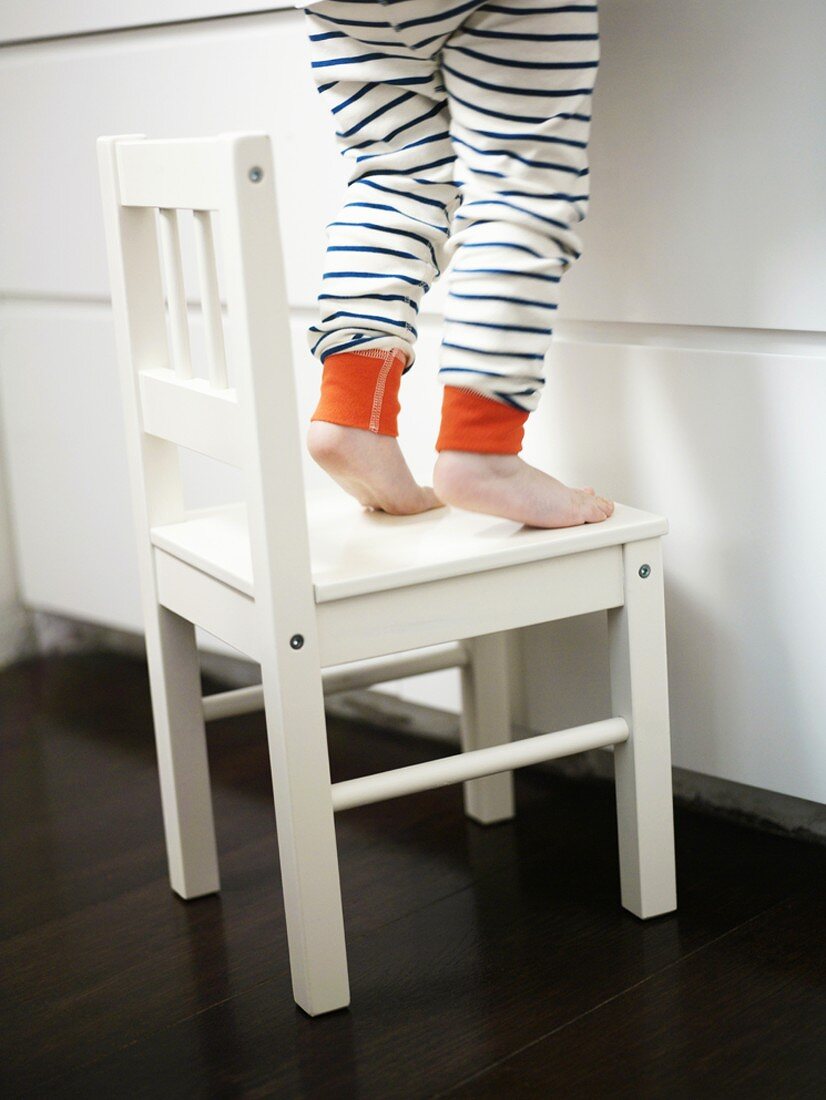 Small child standing on a white chair