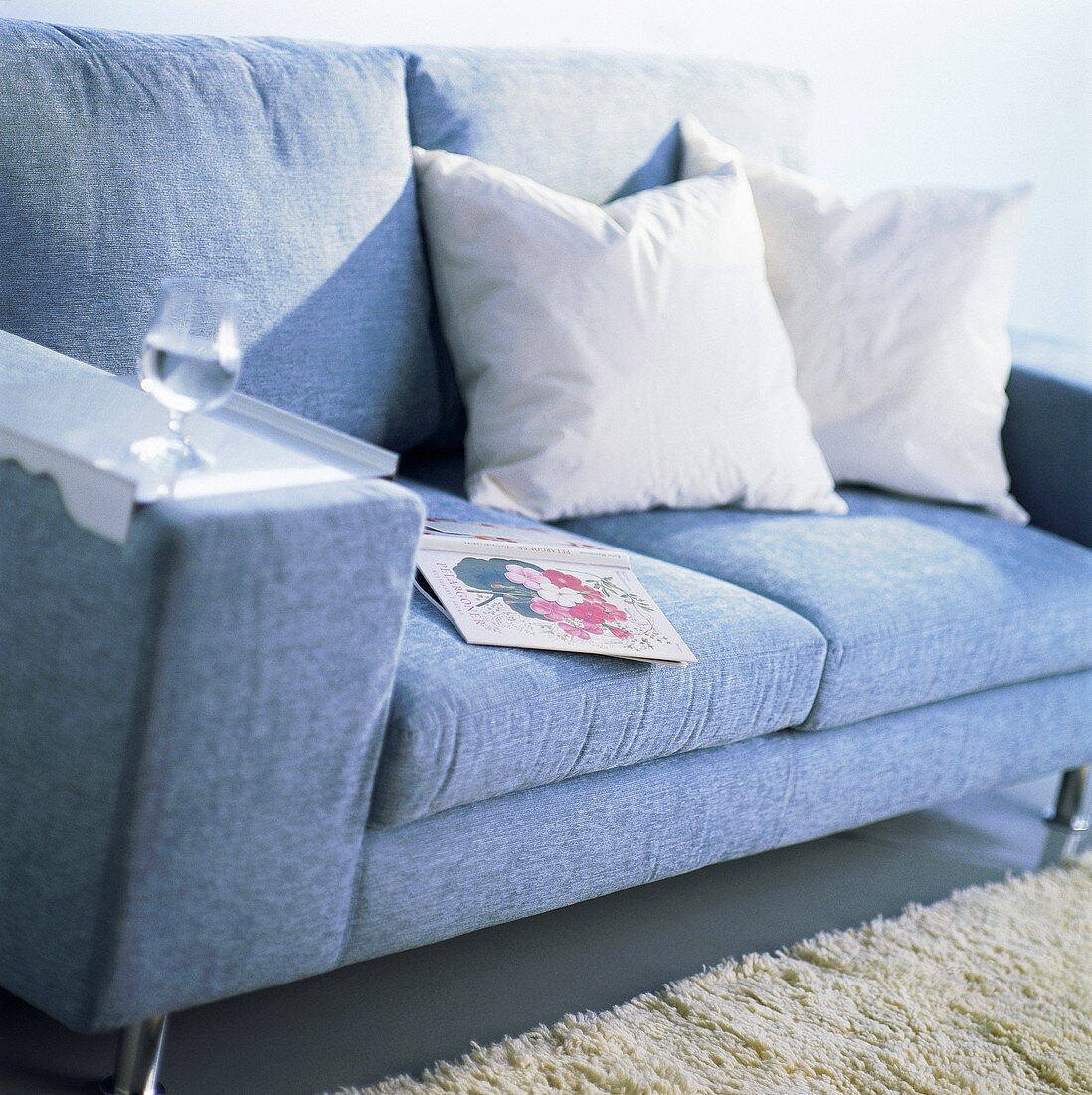 Blue couch with cushions, book and a glass of water