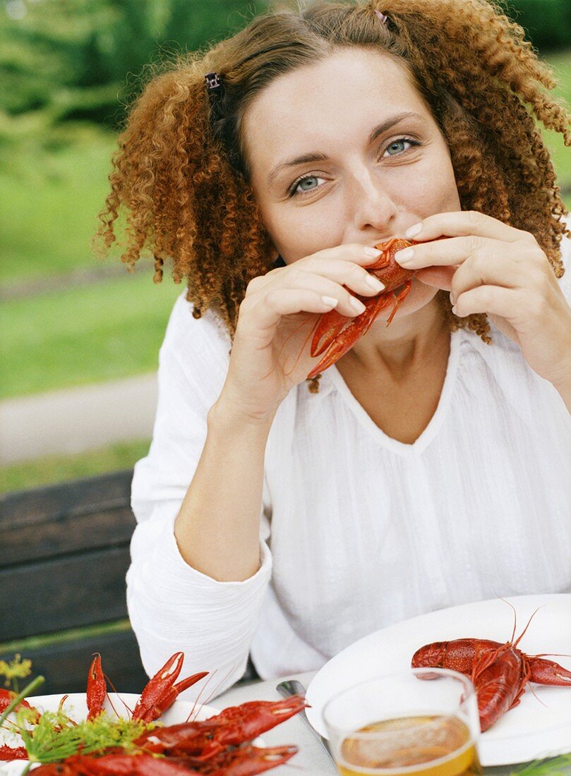 Junge Frau isst Flusskrebs im Freien (Krebsfest, Schweden)