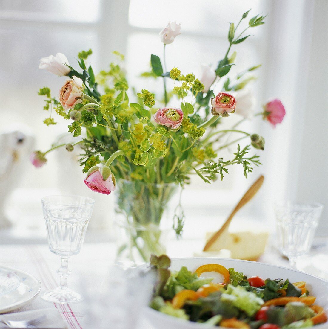 Flowers and bowl of salad on laid table