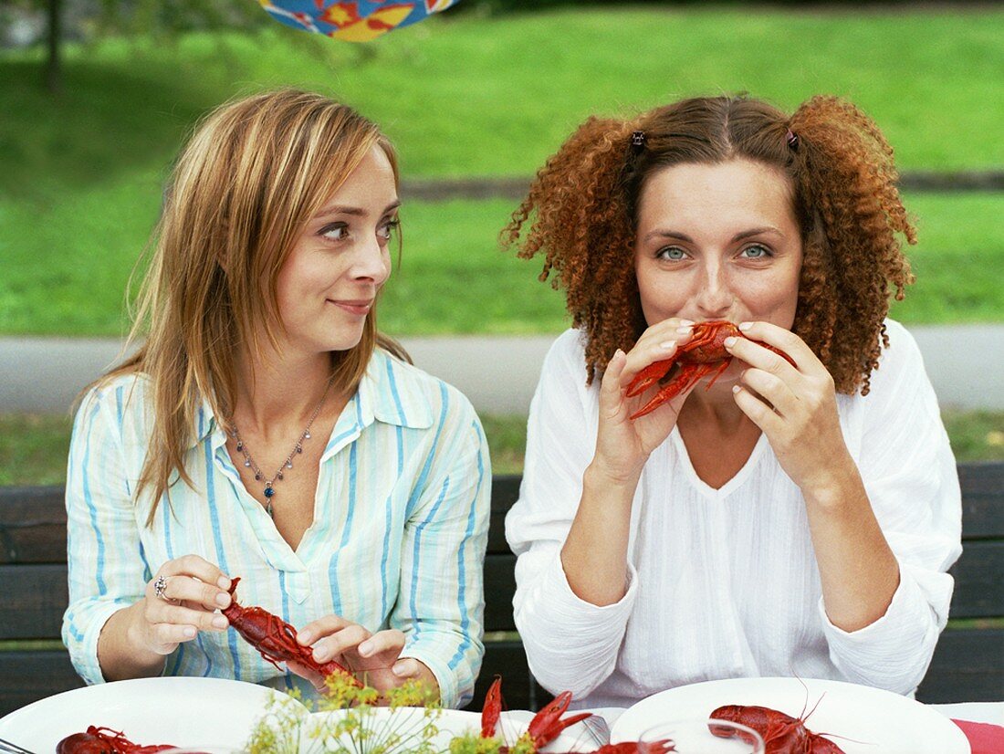 Two women eating crayfish out of doors (Crayfish party, Sweden)