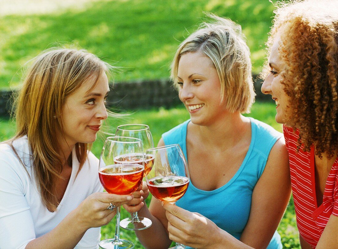 Three friends clinking glasses of rosé sparkling wine