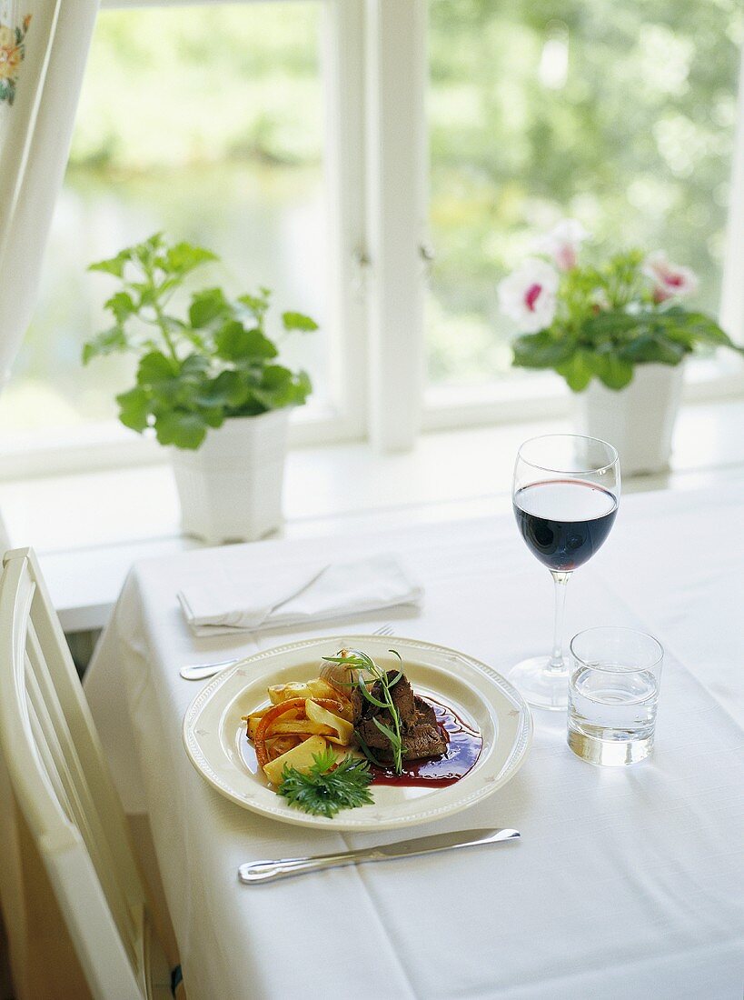 Rinderbraten mit Kartoffeln und ein Glas Rotwein