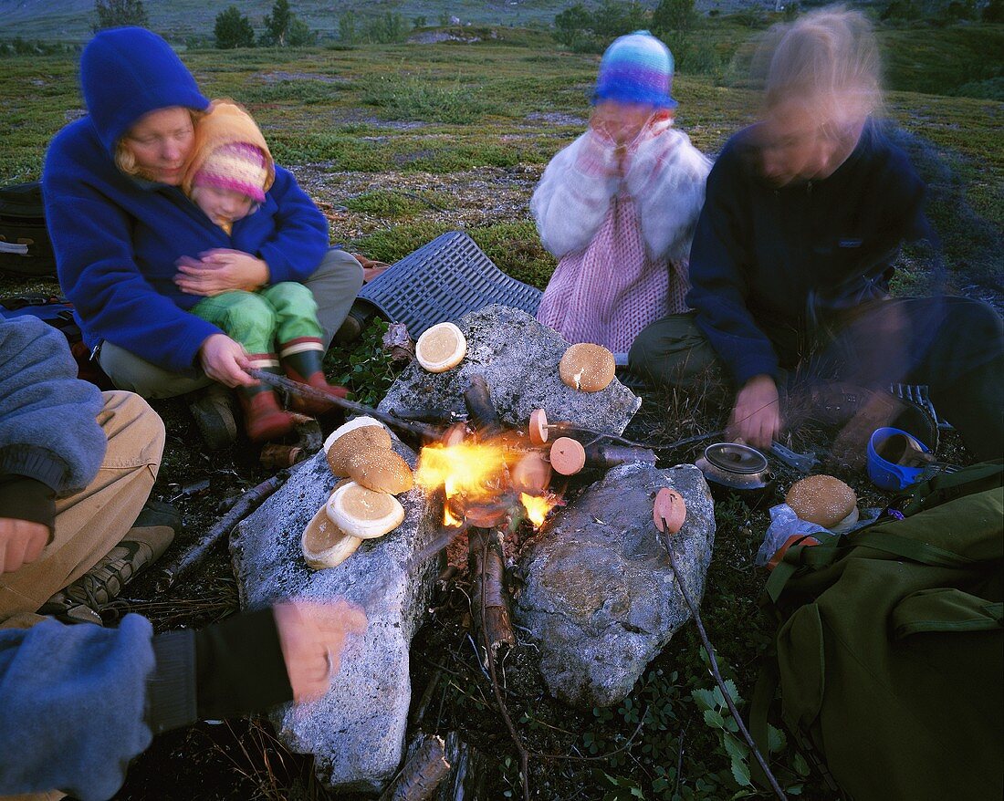 Familie mit kleinen Kindern grillt am offenen Feuer