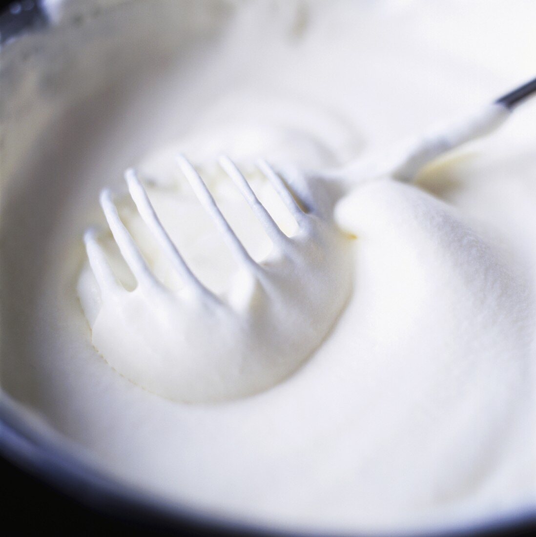Whipped cream with whisk in a bowl
