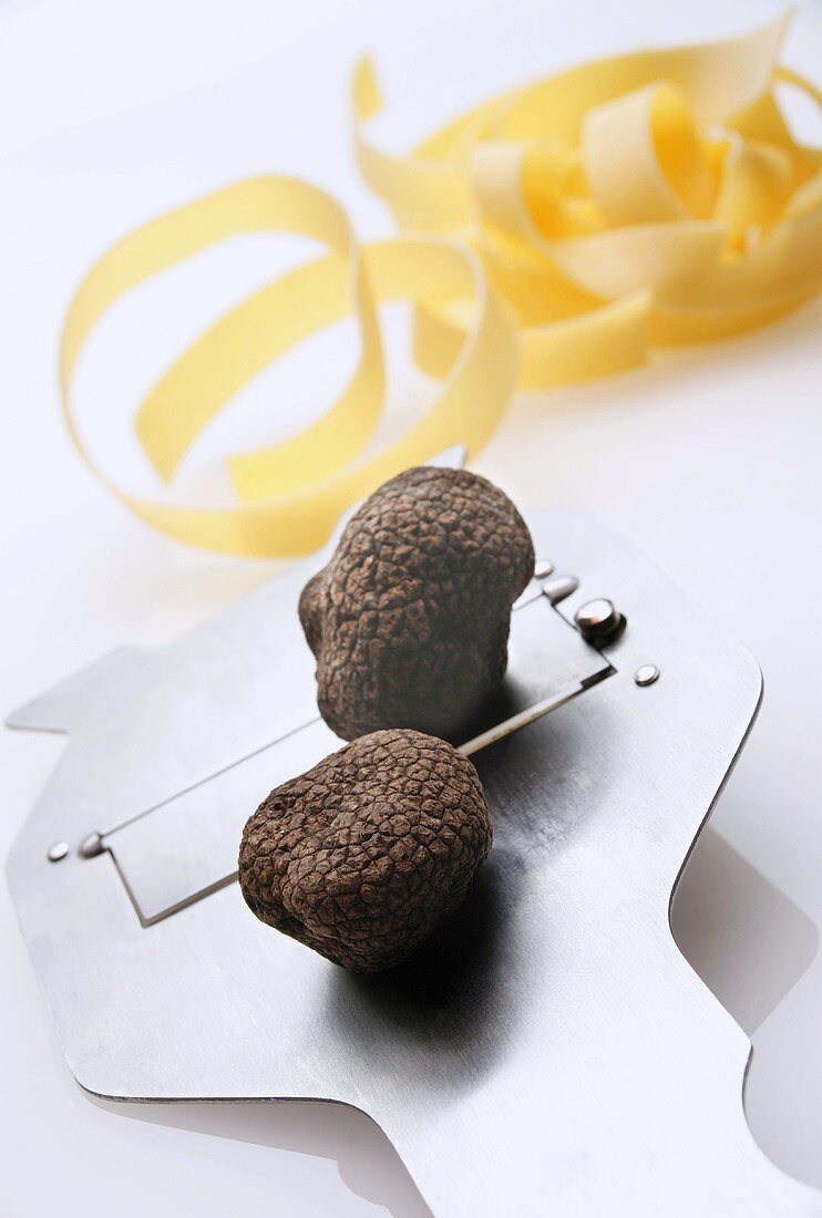 Black truffles (Chinese truffles) on truffle slicer, ribbon pasta